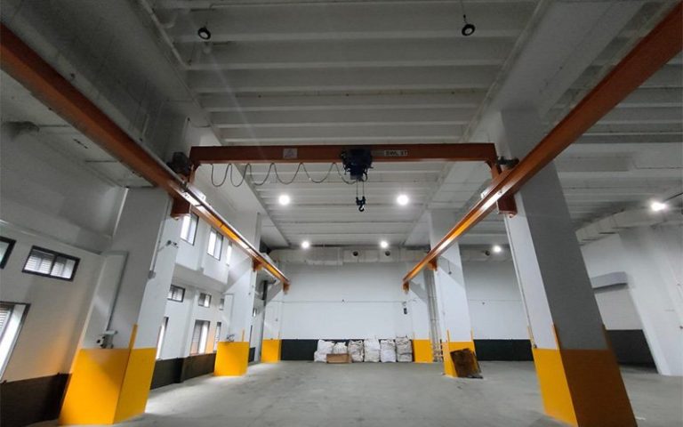 overhead bridge crane installed inside an empty industrial warehouse